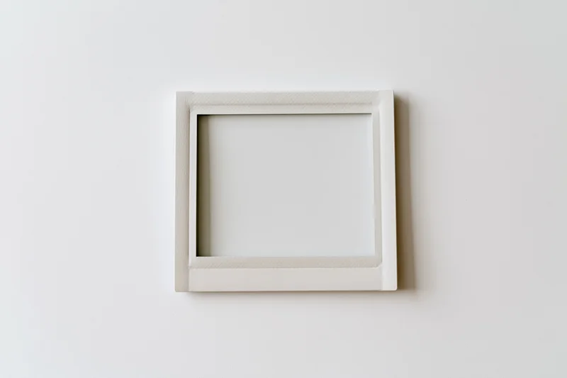 White square frame hanging on a plain wall with blank interior space