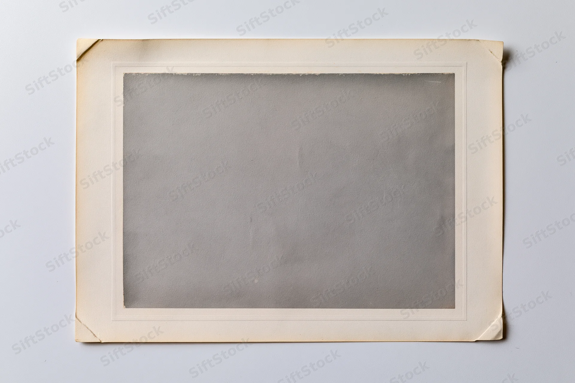 Vintage photo print with aged paper frame lying flat on white surface