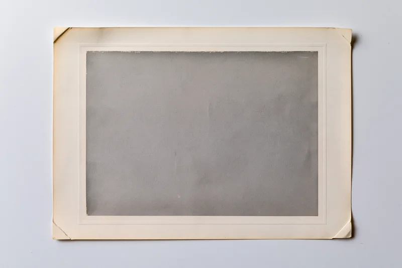 Vintage photo print with aged paper frame lying flat on white surface