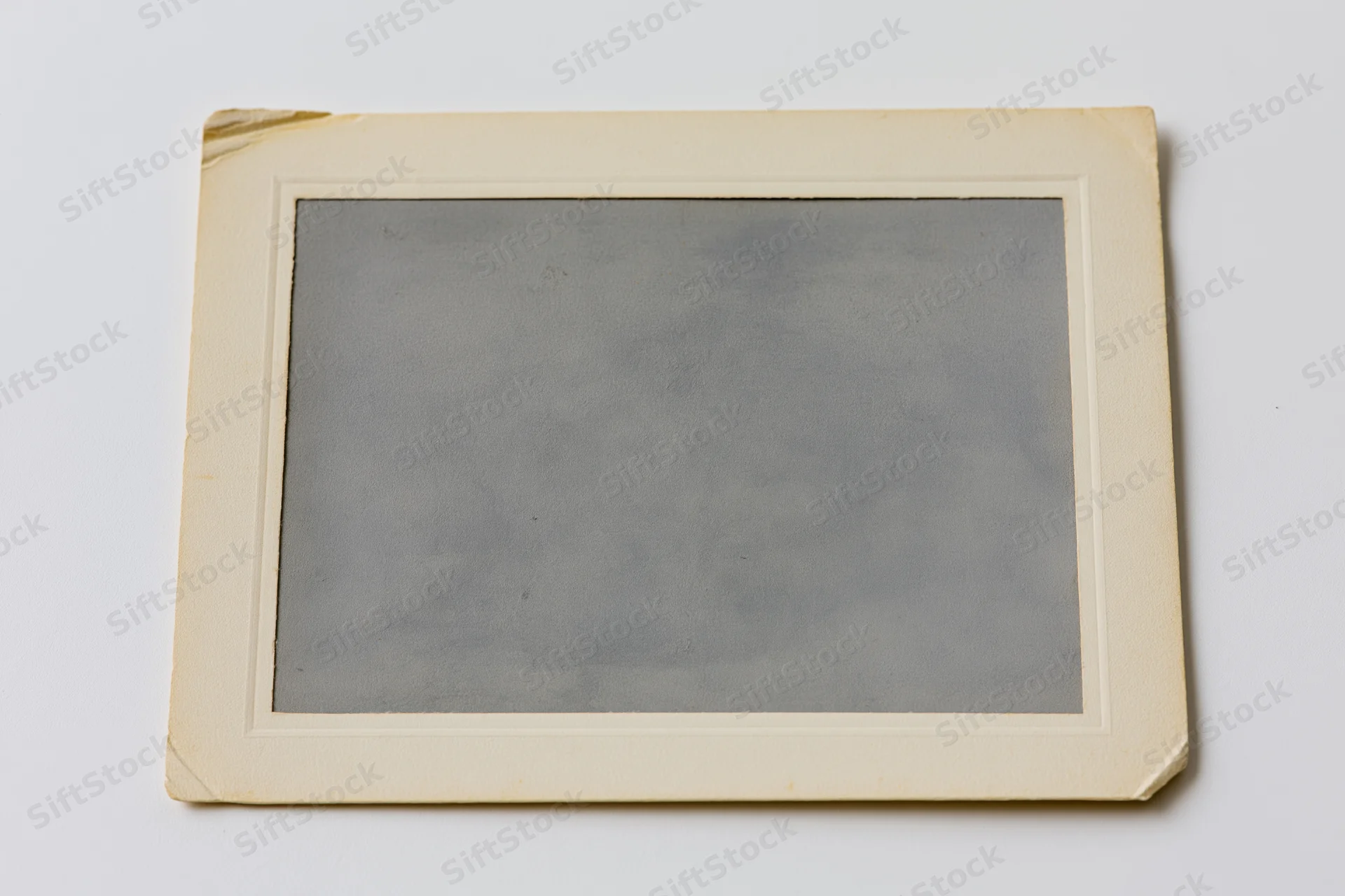 Vintage photograph print with aged paper frame lying flat on white surface