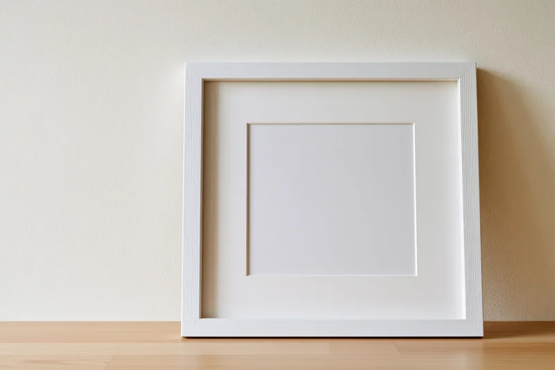 White square picture frame with white mat leaning against a beige wall on wooden floor