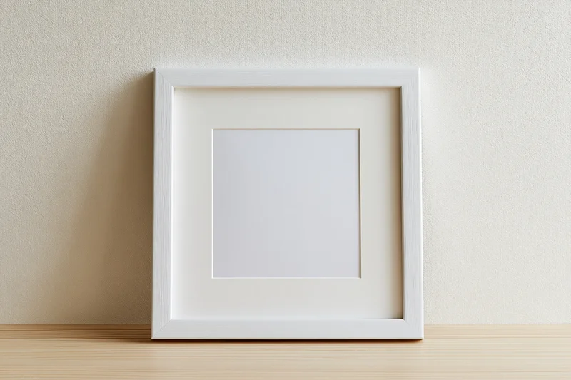 White square picture frame with mat leaning against textured wall on wooden shelf