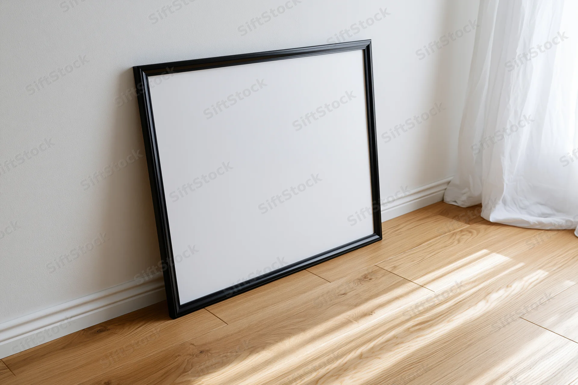 Black picture frame leaning against white wall on wooden floor near window with sheer curtain