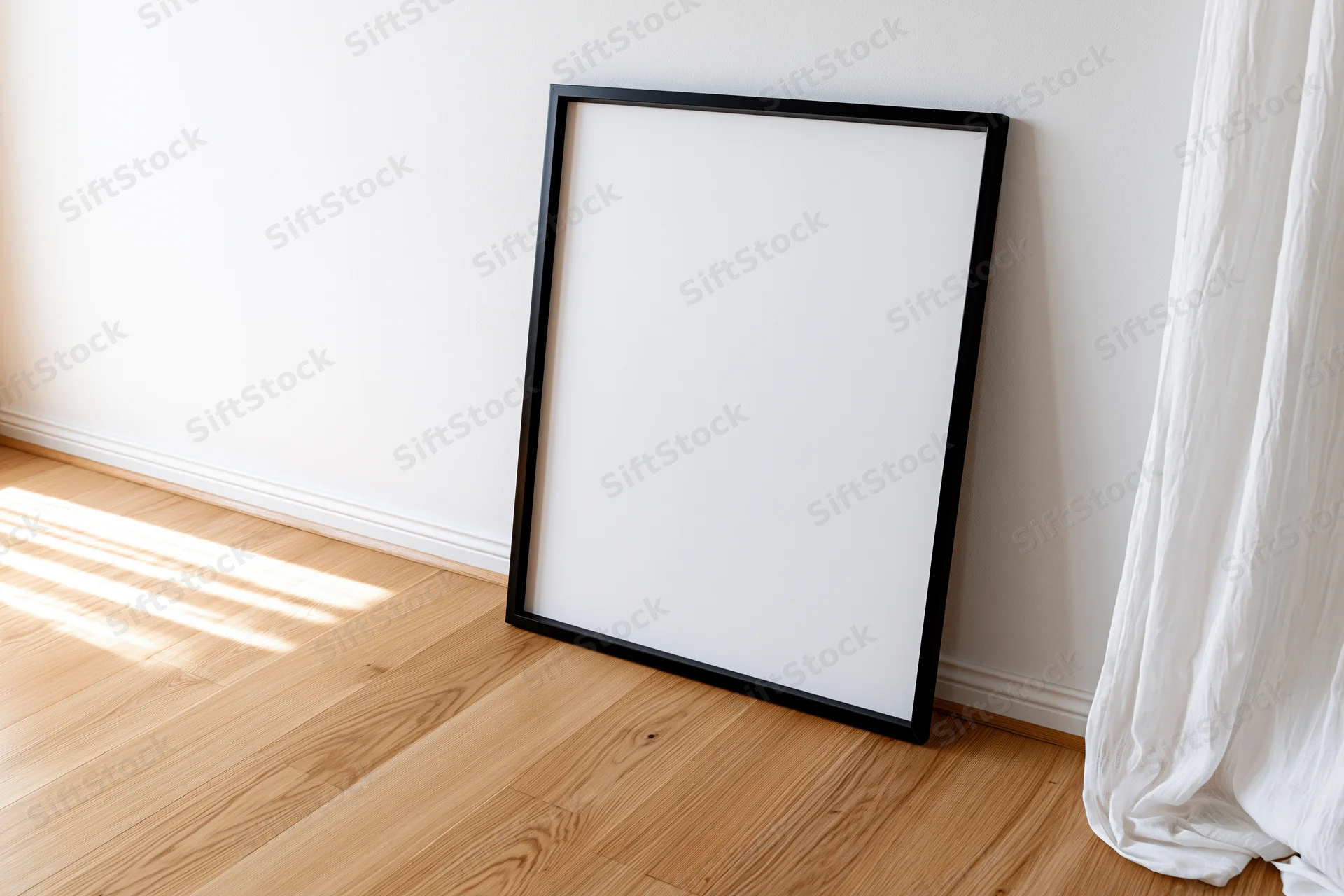 Black picture frame leaning against white wall on wooden floor near window with curtain