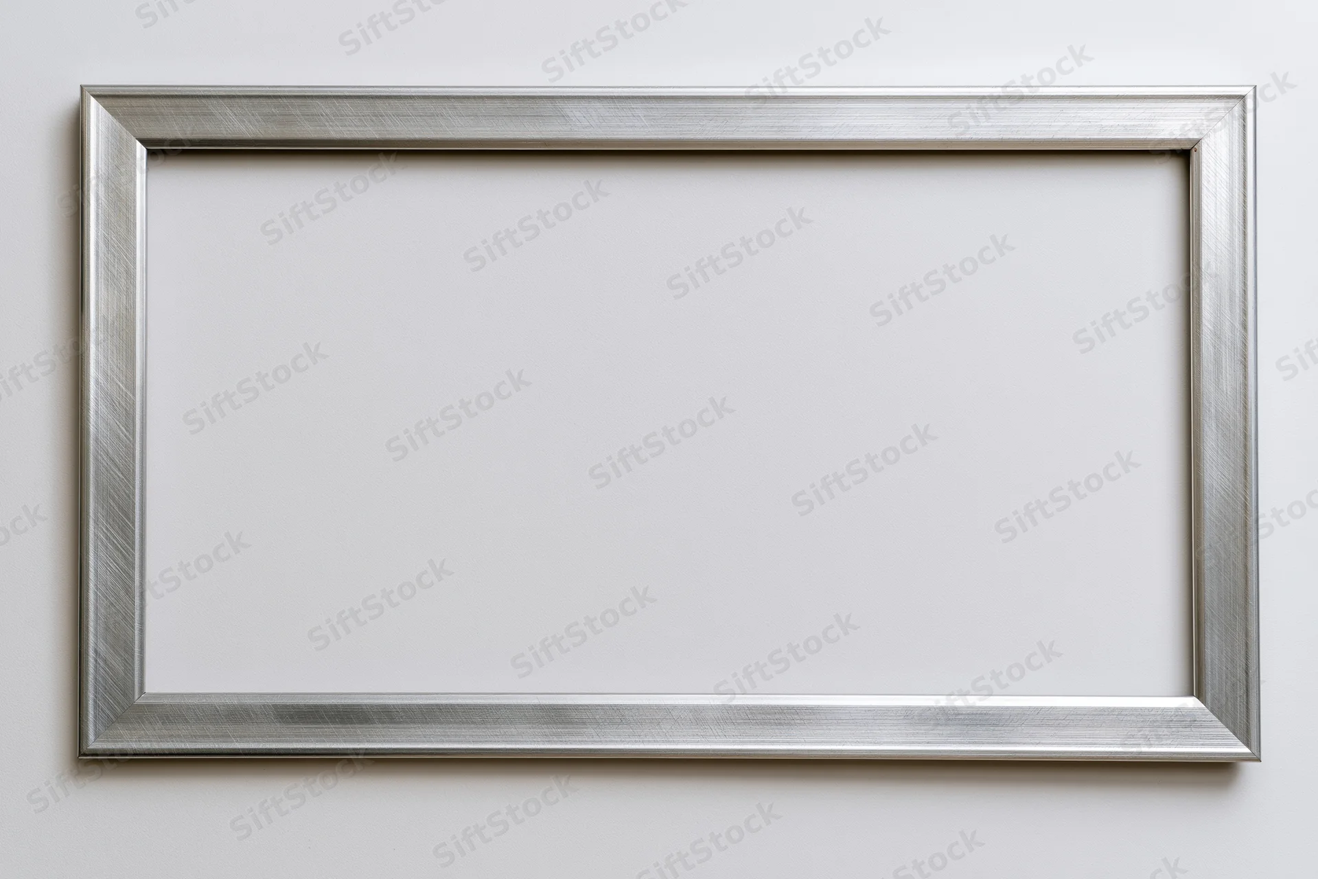 Silver metallic picture frame hanging on a white wall with empty center for display