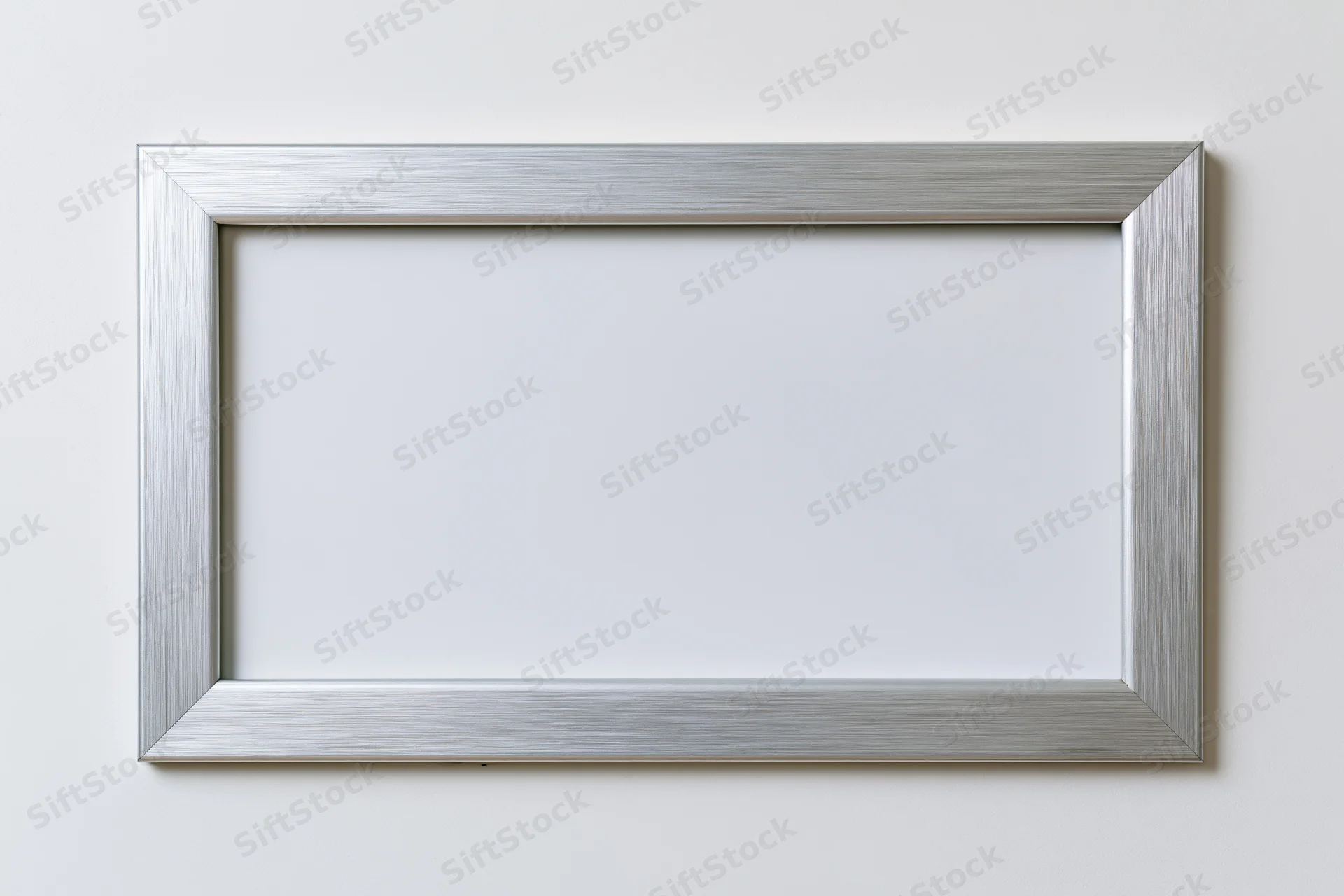 Silver brushed metallic picture frame hanging on white wall with empty white mat inside