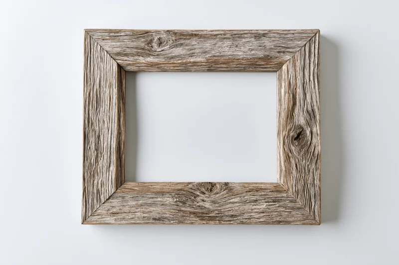 Weathered wooden frame with empty white center hanging on a plain wall