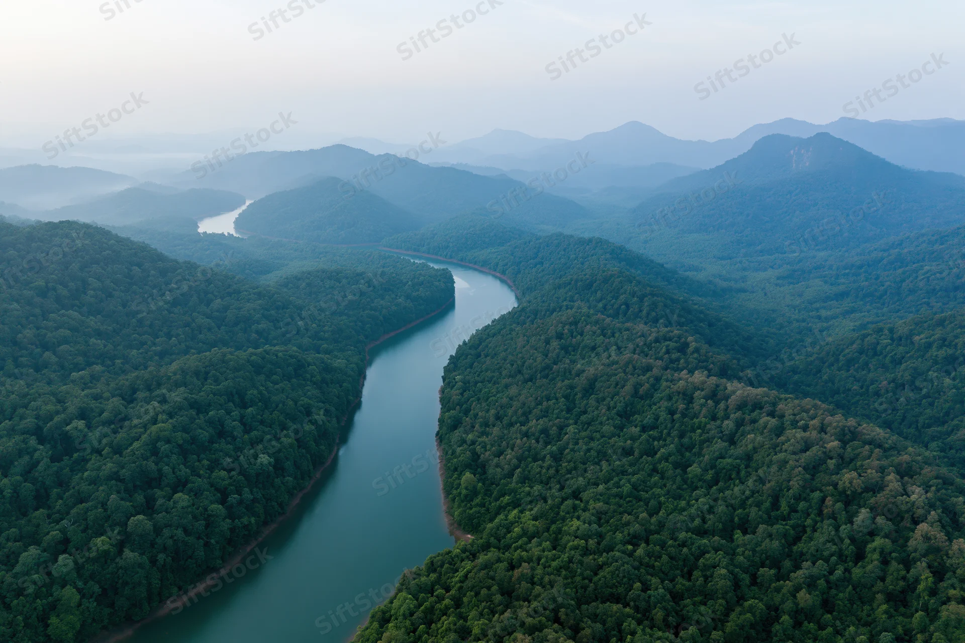Aerial view of a winding river cutting through dense tropical forest