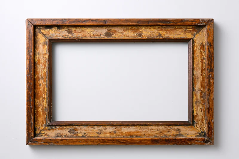 Old wooden picture frame with chipped paint hanging on a white wall