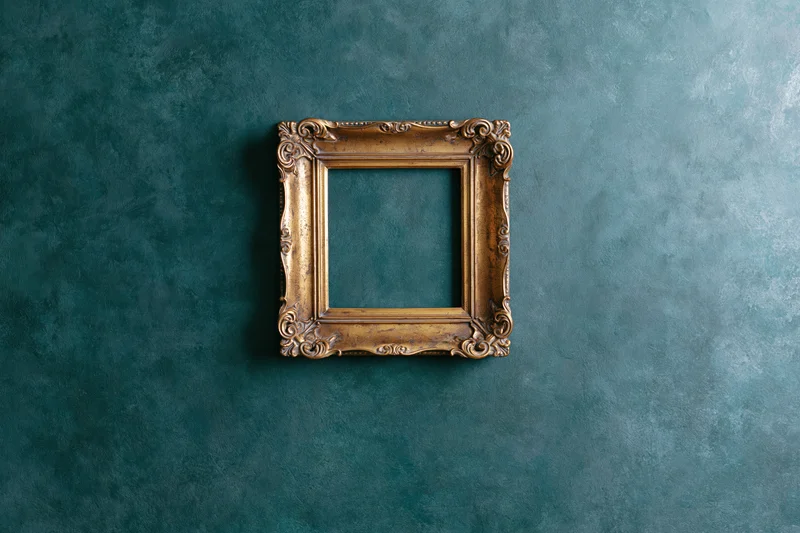 Ornate antique gold frame hanging empty on textured teal wall