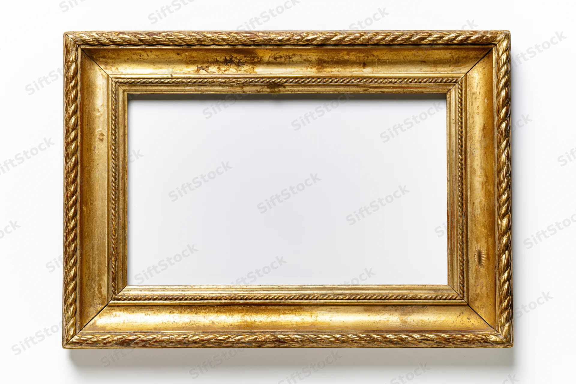 Ornate antique gold picture frame lying flat with empty interior on white background