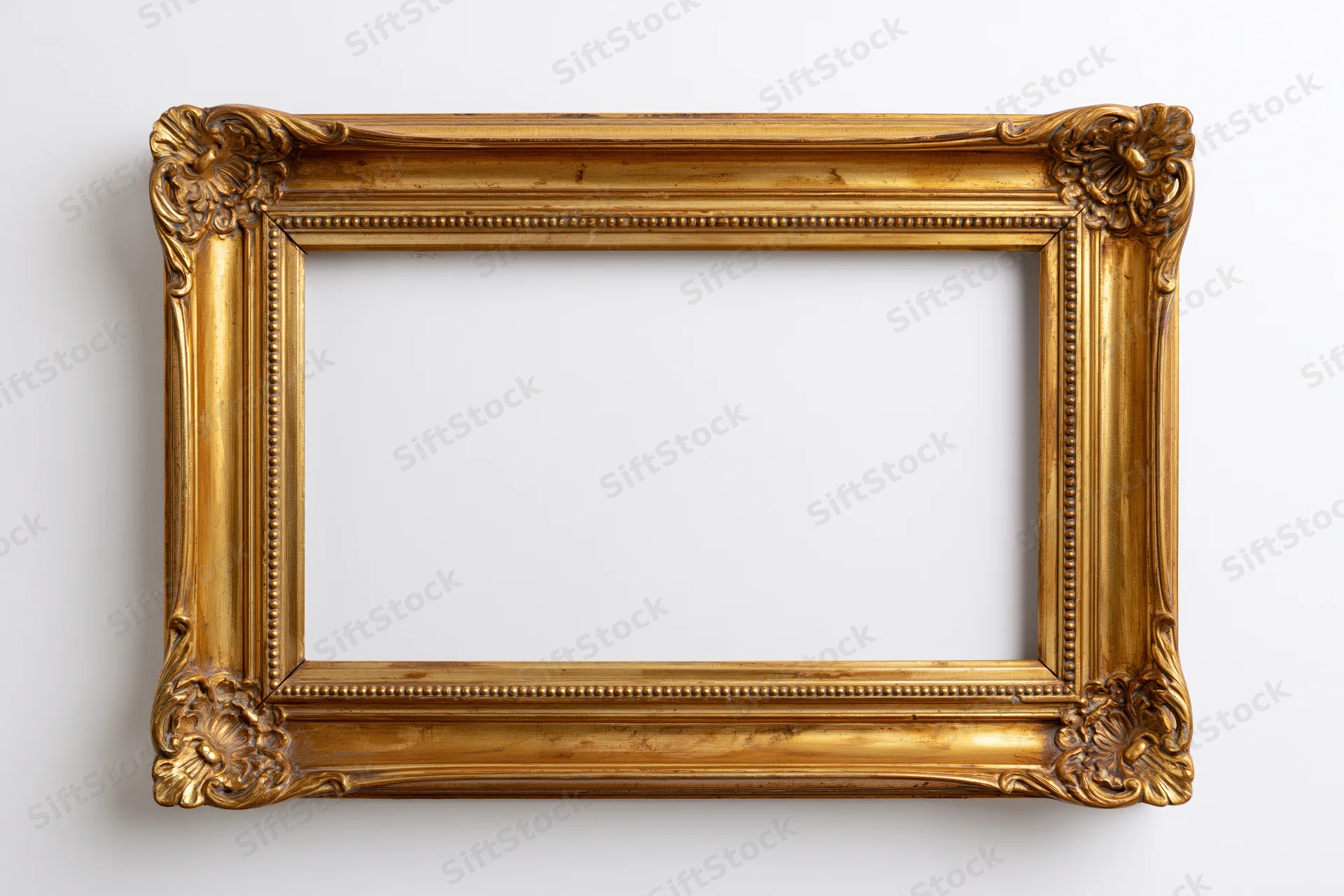 Ornate antique gold picture frame with carved floral corners hanging on white wall