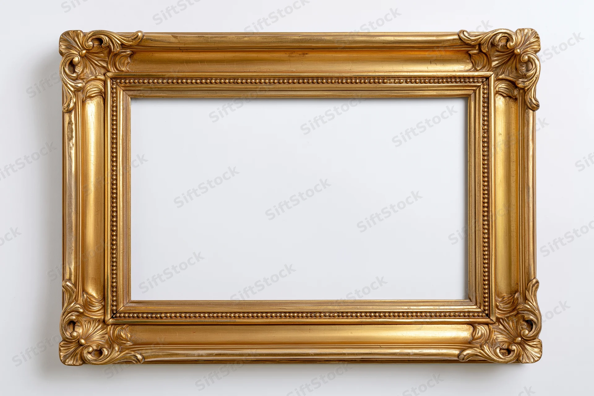 Ornate gold picture frame with carved floral corners hanging on white wall