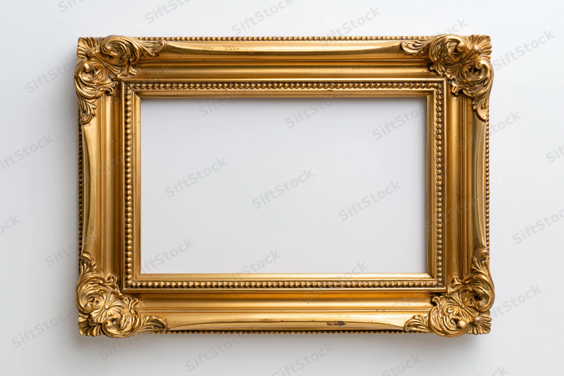 Ornate gold picture frame with carved floral corners hanging on white wall