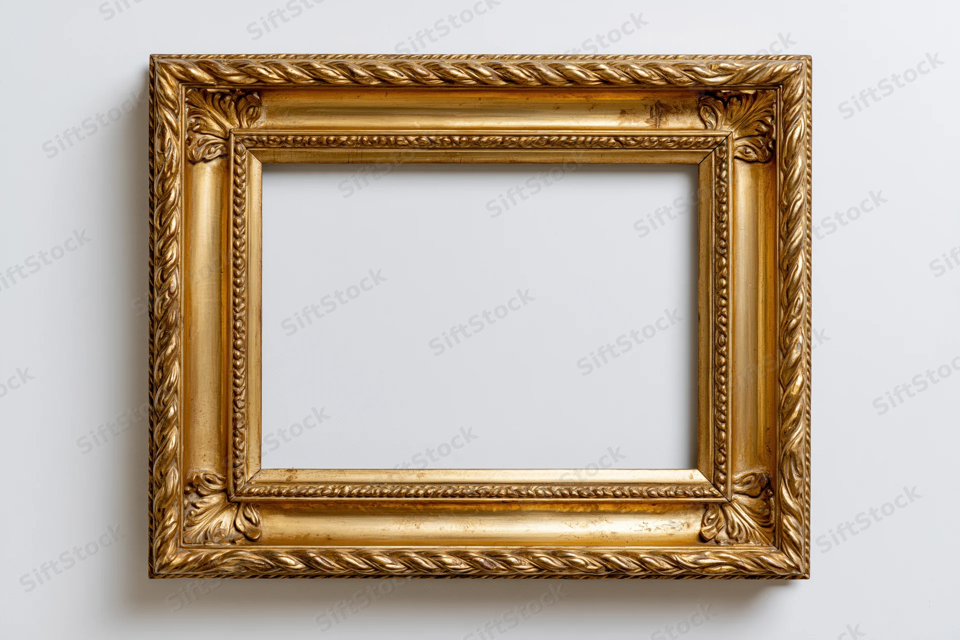 Ornate gold picture frame with carved rope and leaf details hanging on white wall