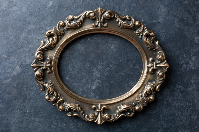 Ornate oval brass frame with baroque scrollwork on dark textured surface