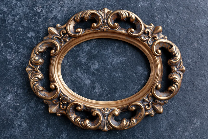 Ornate oval brass frame with baroque scrollwork on dark stone surface