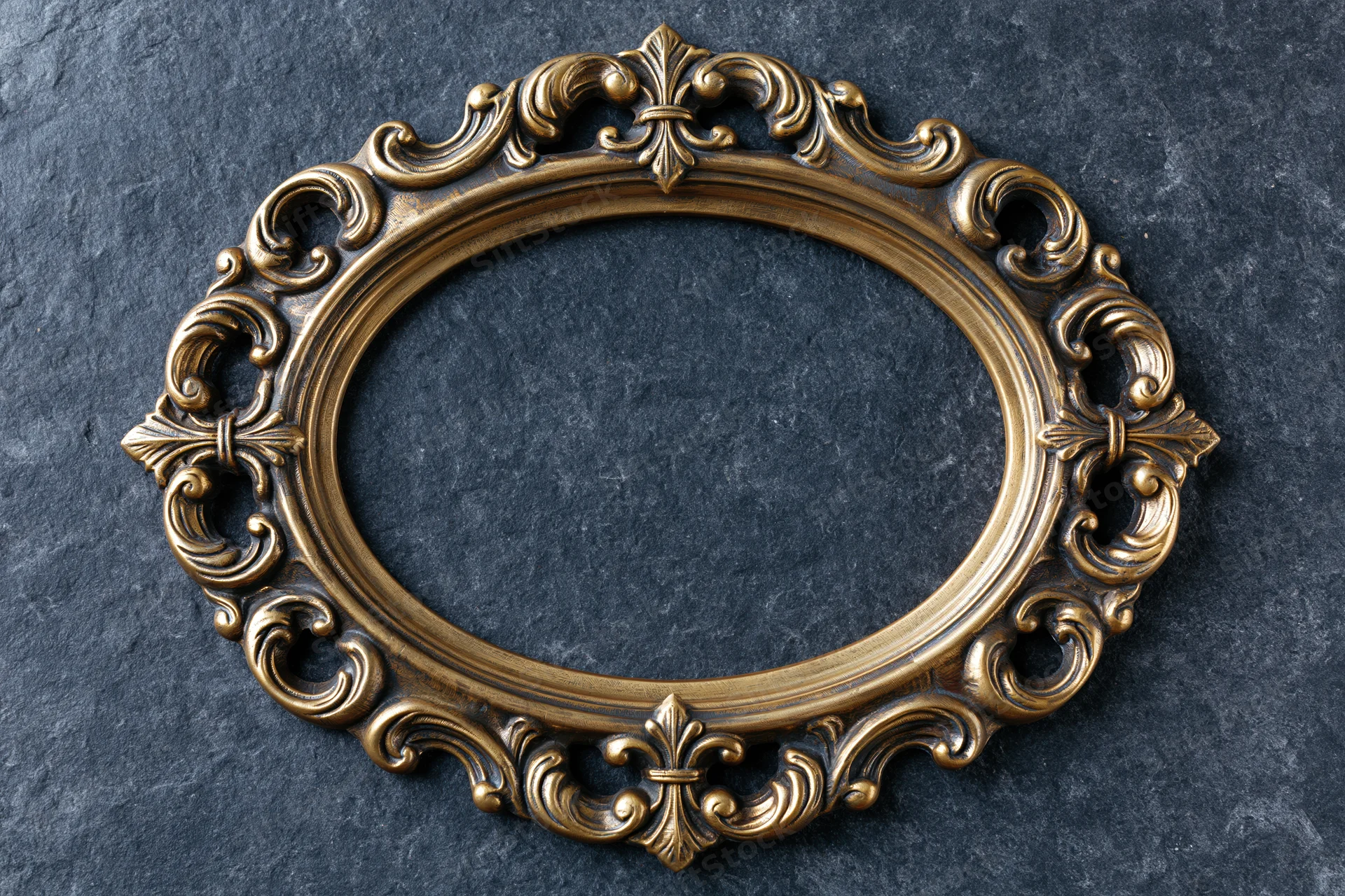 Ornate oval brass frame with baroque scrollwork on dark stone surface