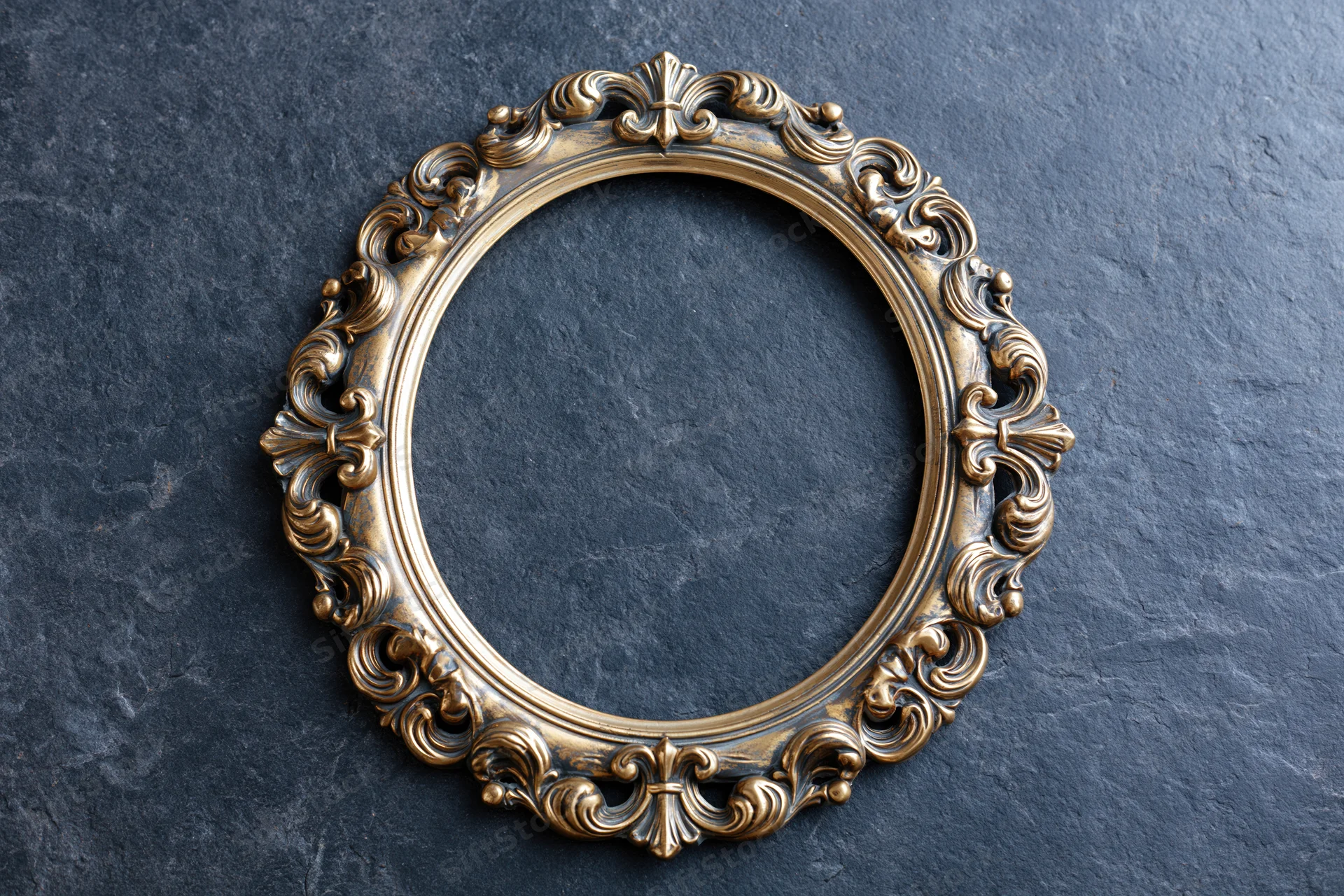 Ornate brass oval frame with baroque scrollwork resting on dark stone surface
