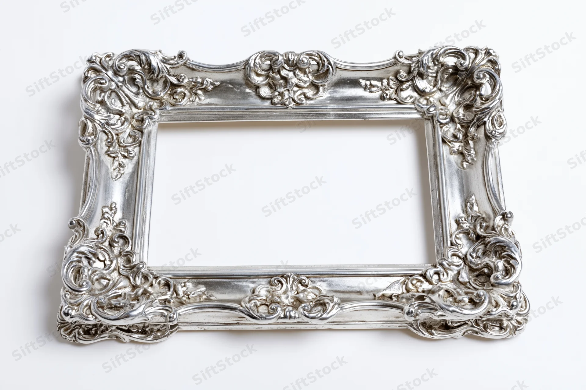 Ornate silver baroque picture frame with intricate scrollwork on white background