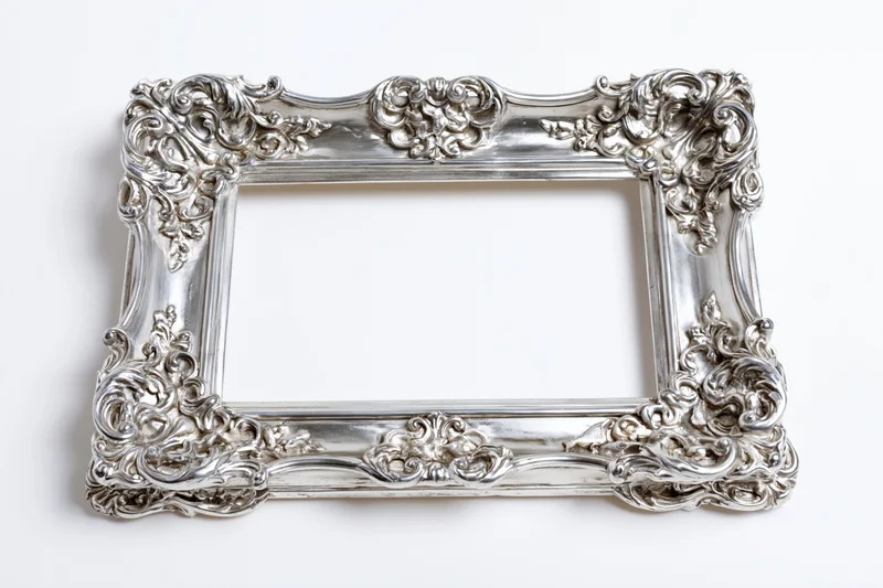 Ornate silver baroque picture frame with intricate scrollwork on white background