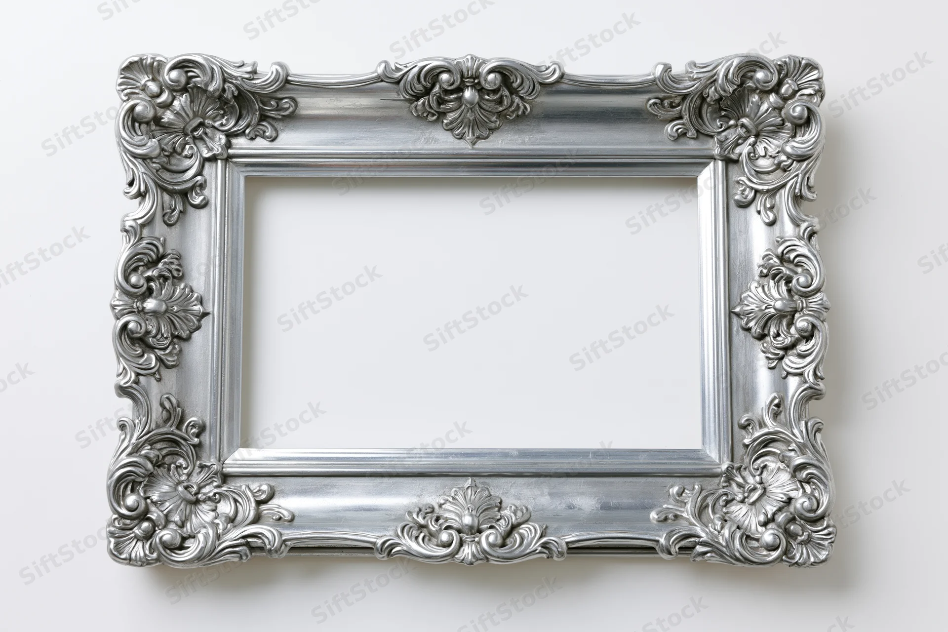 Ornate silver baroque frame with intricate scrollwork hanging on white wall
