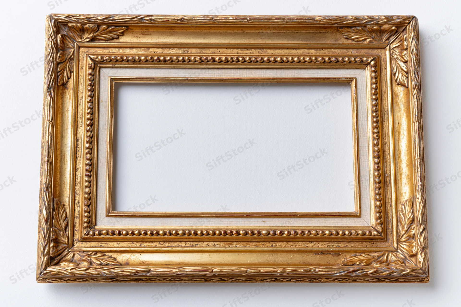 Ornate antique gold picture frame lying flat on white background with empty interior