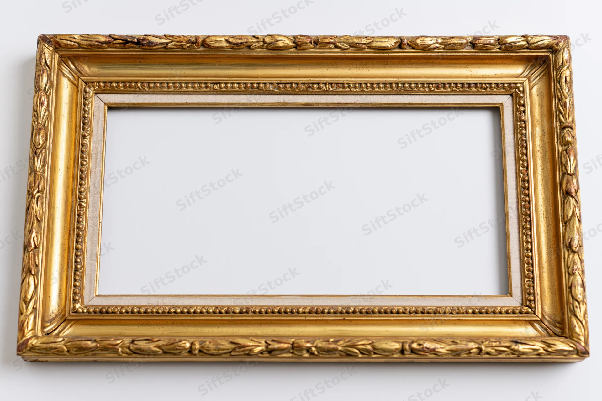 Ornate antique gold picture frame lying flat with empty interior on white background