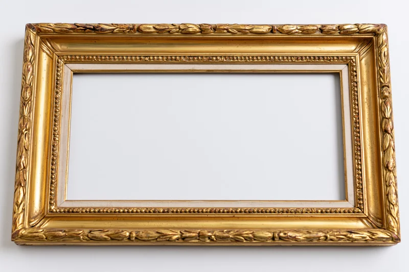 Ornate antique gold picture frame lying flat with empty interior on white background