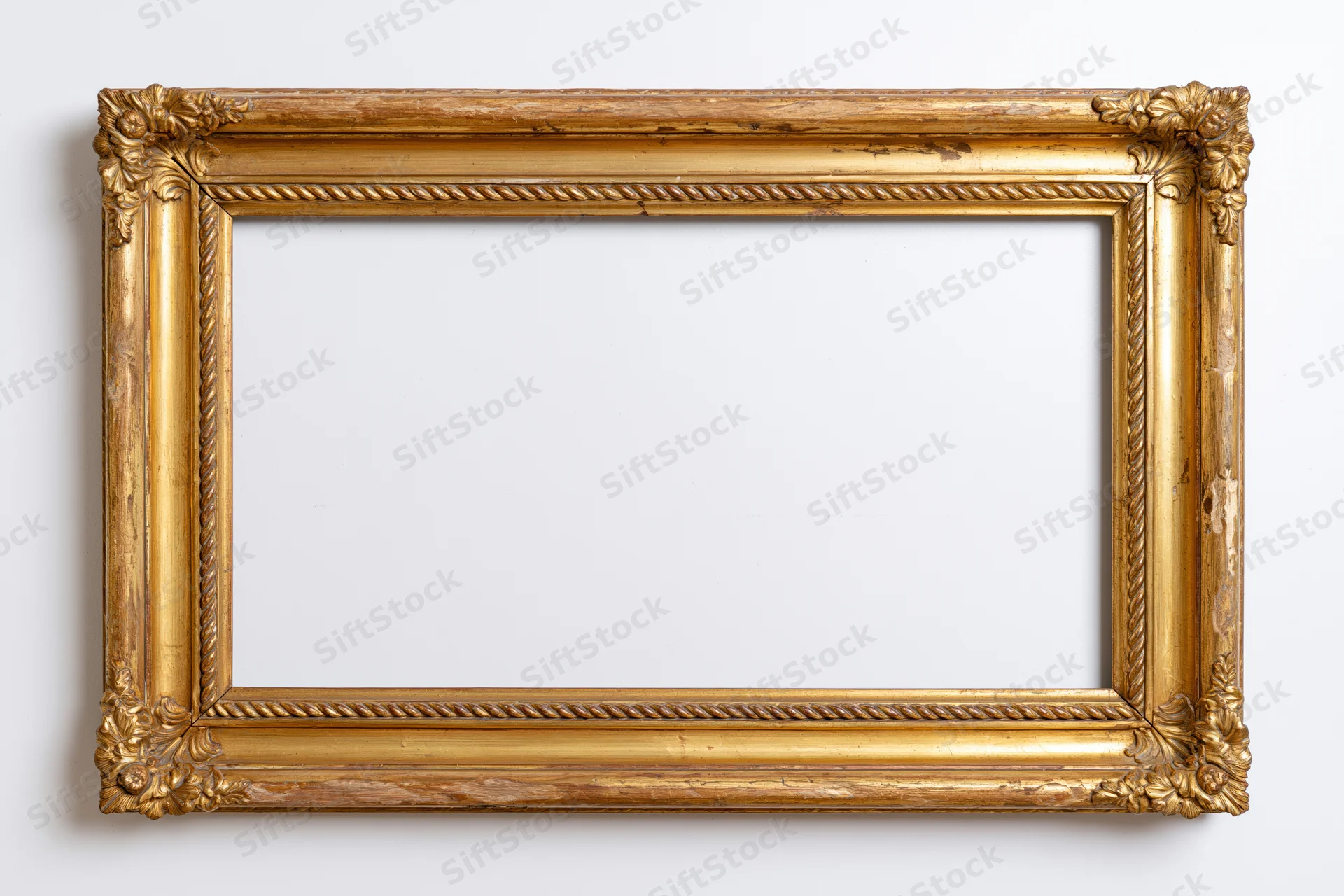 Ornate antique gold picture frame with carved corner details hanging on white wall