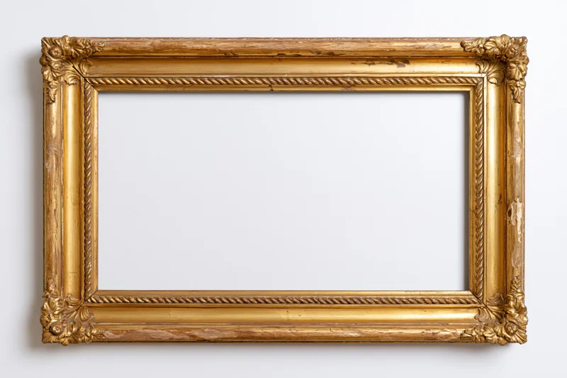 Ornate antique gold picture frame with carved corner details hanging on white wall