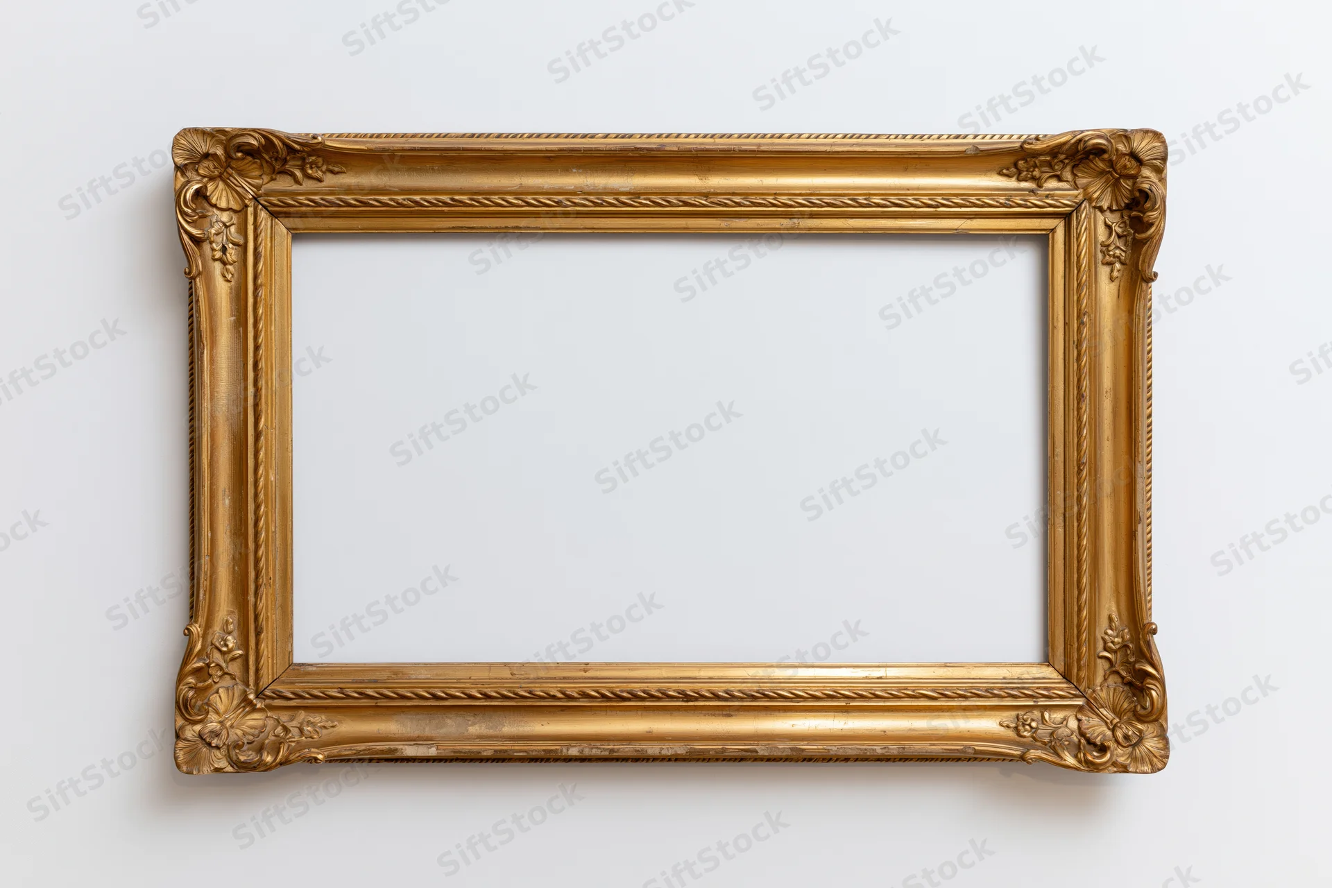 Ornate antique gold picture frame with carved corner details hanging on a white wall