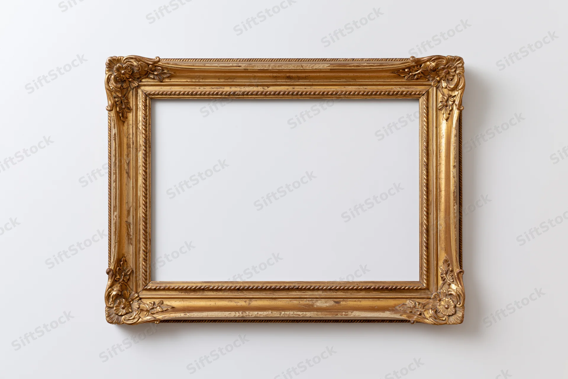 Ornate antique gold picture frame with carved floral details hanging on a white wall