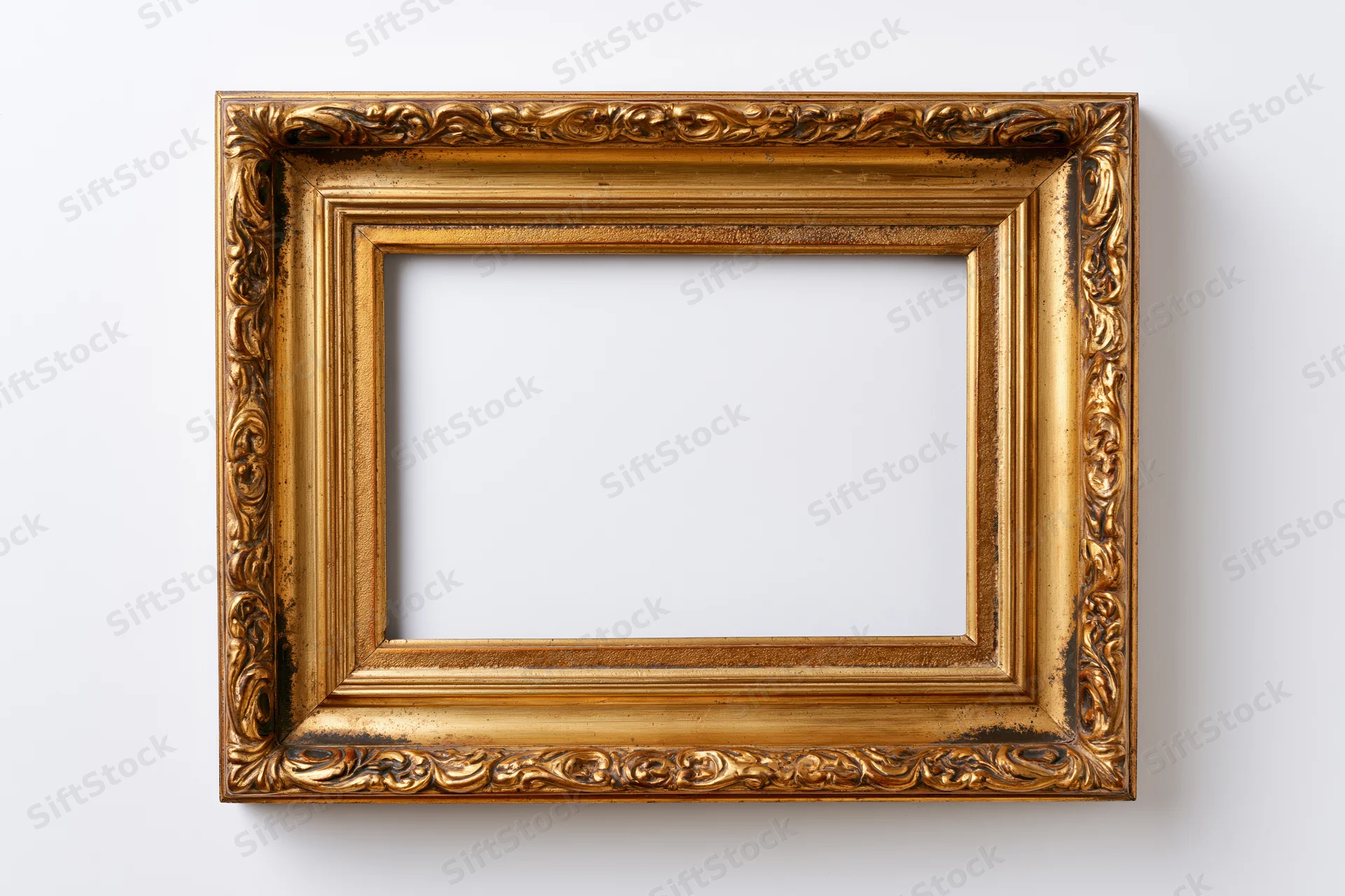 Ornate antique gold picture frame with embossed border detail hanging on white wall