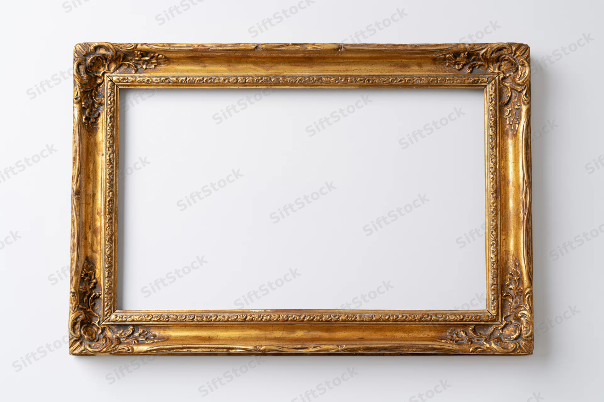 Ornate antique gold picture frame with embossed border detail hanging on white wall