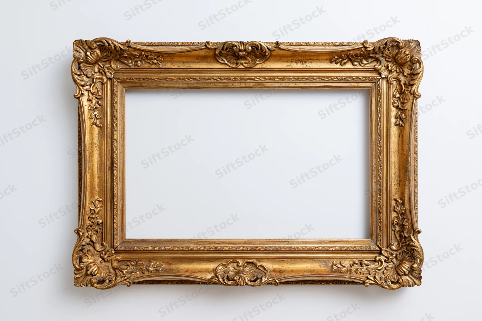 Ornate antique gold picture frame hanging on white wall with empty center for display