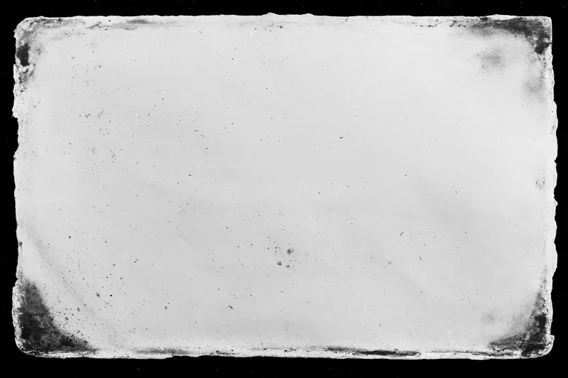 Aged photographic paper with distressed edges lying flat on black background