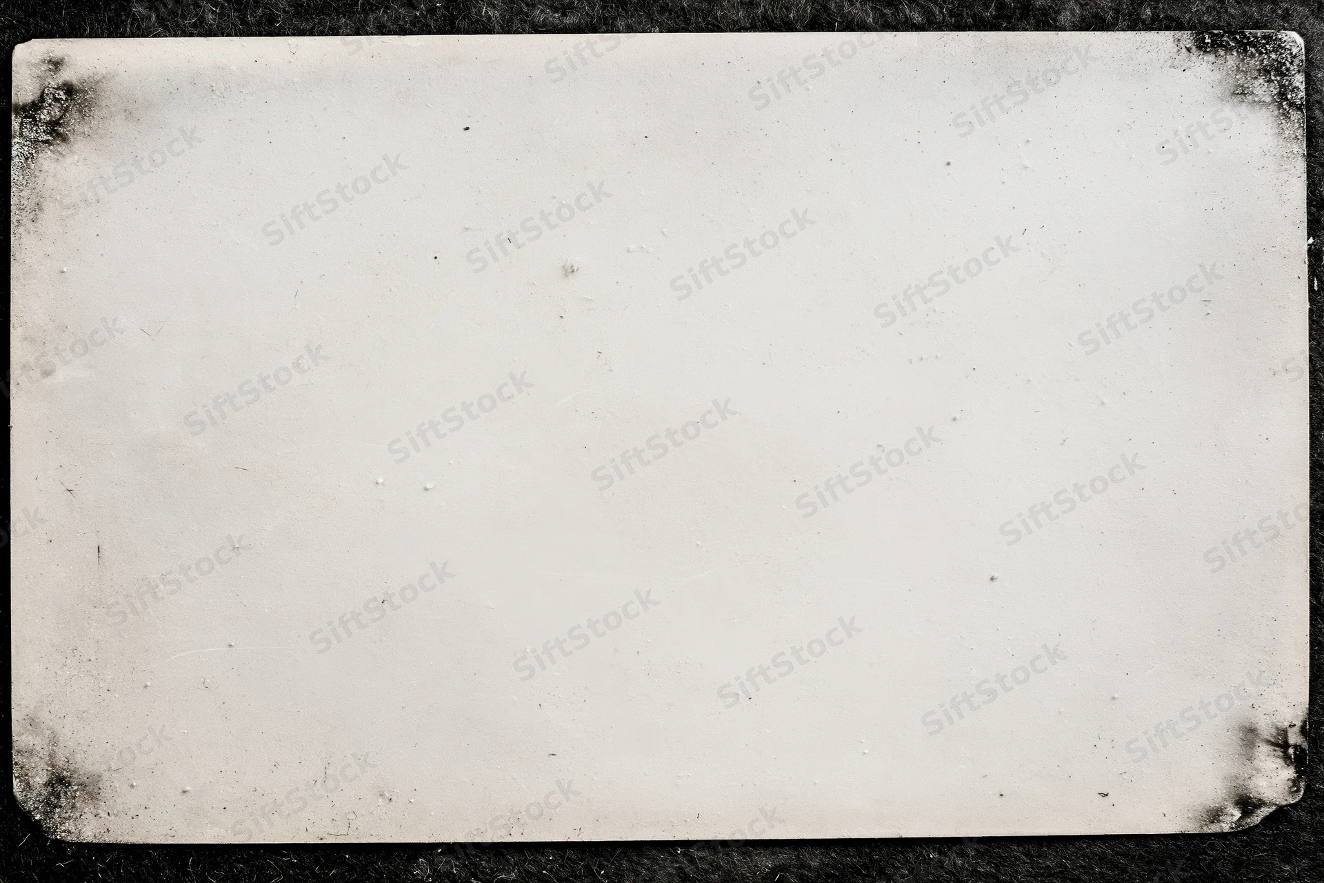 Aged photographic paper with distressed edges lying flat on dark surface