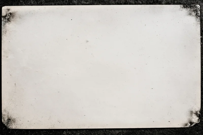 Aged photographic paper with distressed edges lying flat on dark surface