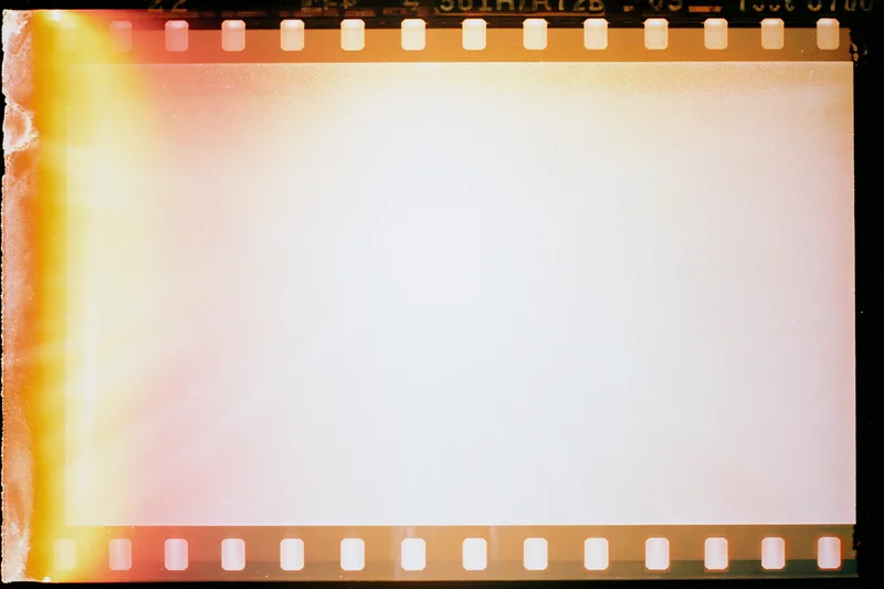 Blank overexposed 35mm film frame with light leak bleed and sprocket holes