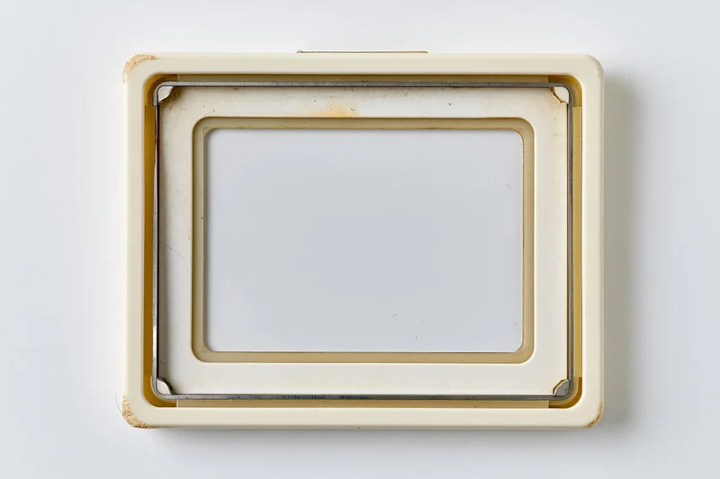 Vintage 35mm slide mount frame with empty white center on plain background