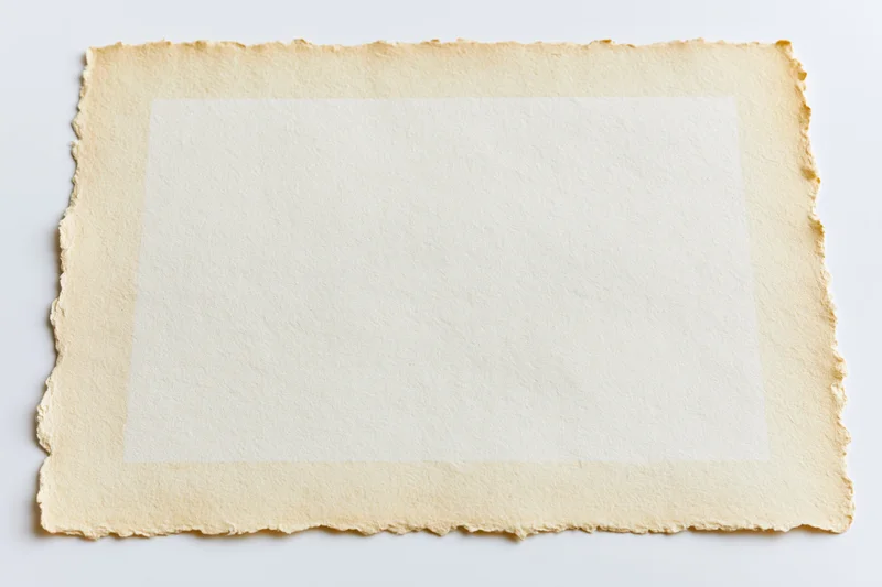 Vintage paper with deckled edges lying flat on white background