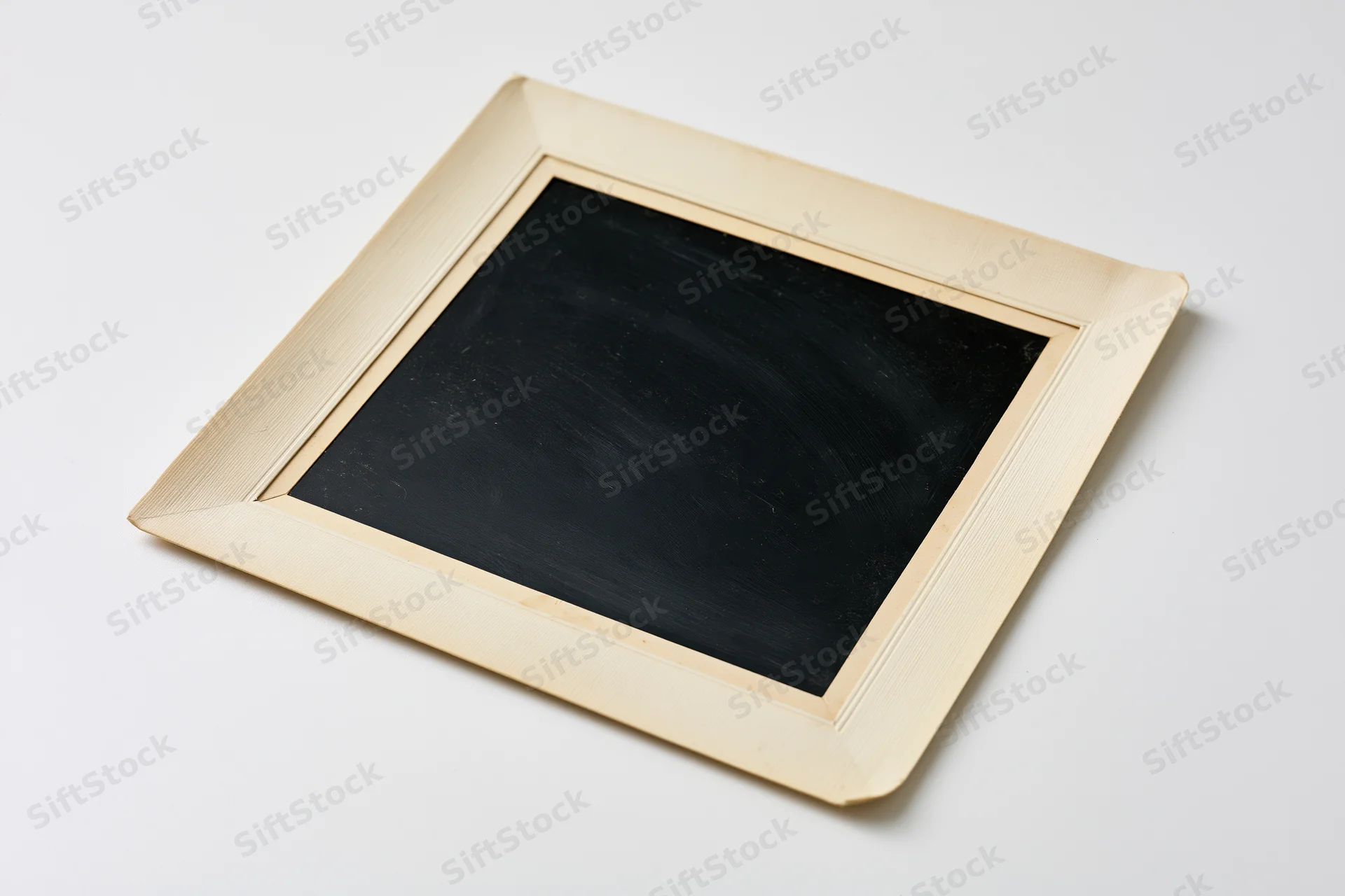 Square chalkboard with wooden frame lying flat on white surface