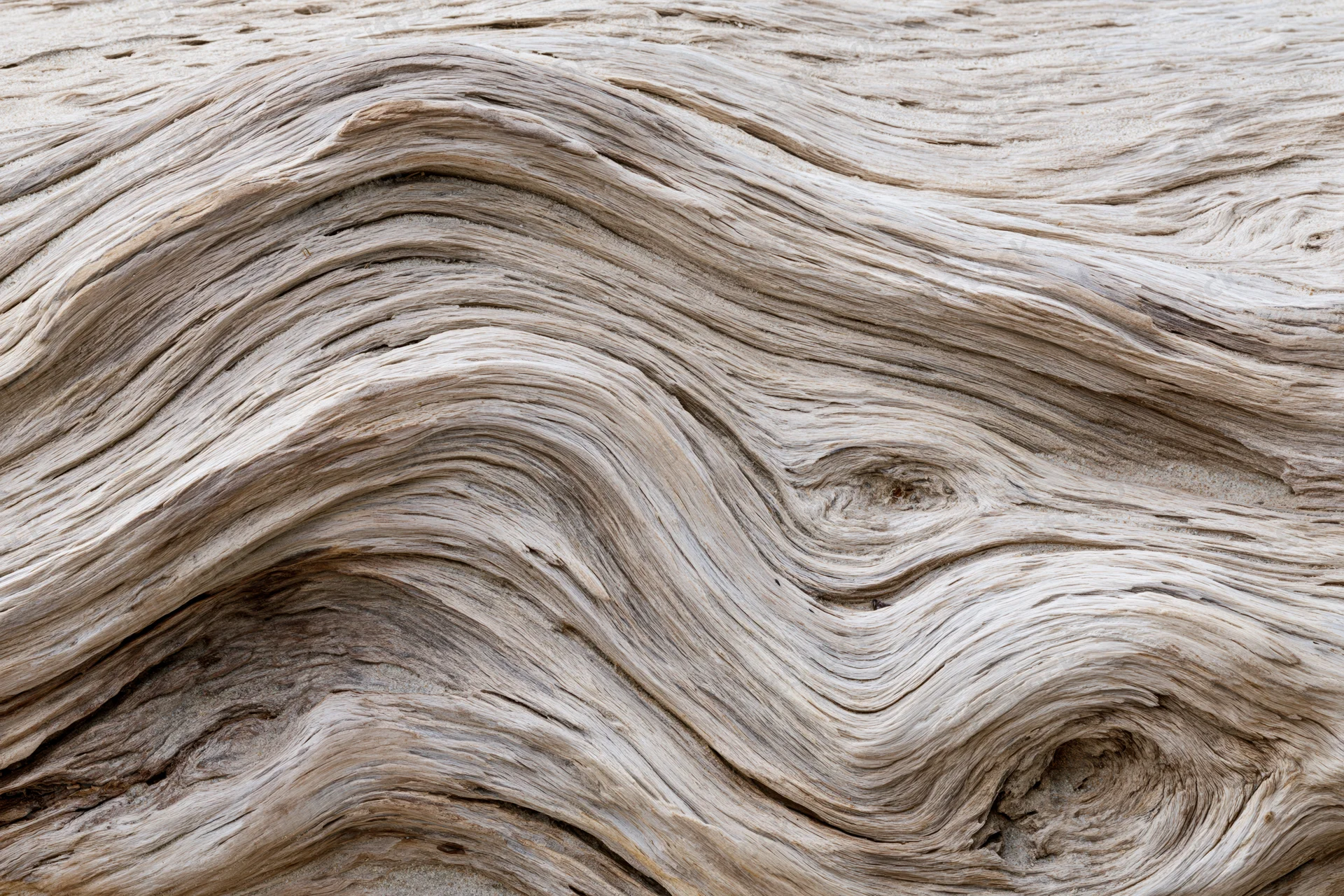 Close-up of weathered driftwood surface showing wavy grain patterns and natural texture