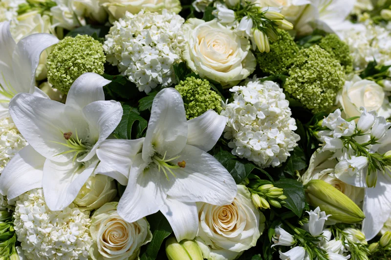 Close-up of a dense white floral arrangement with lilies, roses and hydrangeas laid flat on a surface