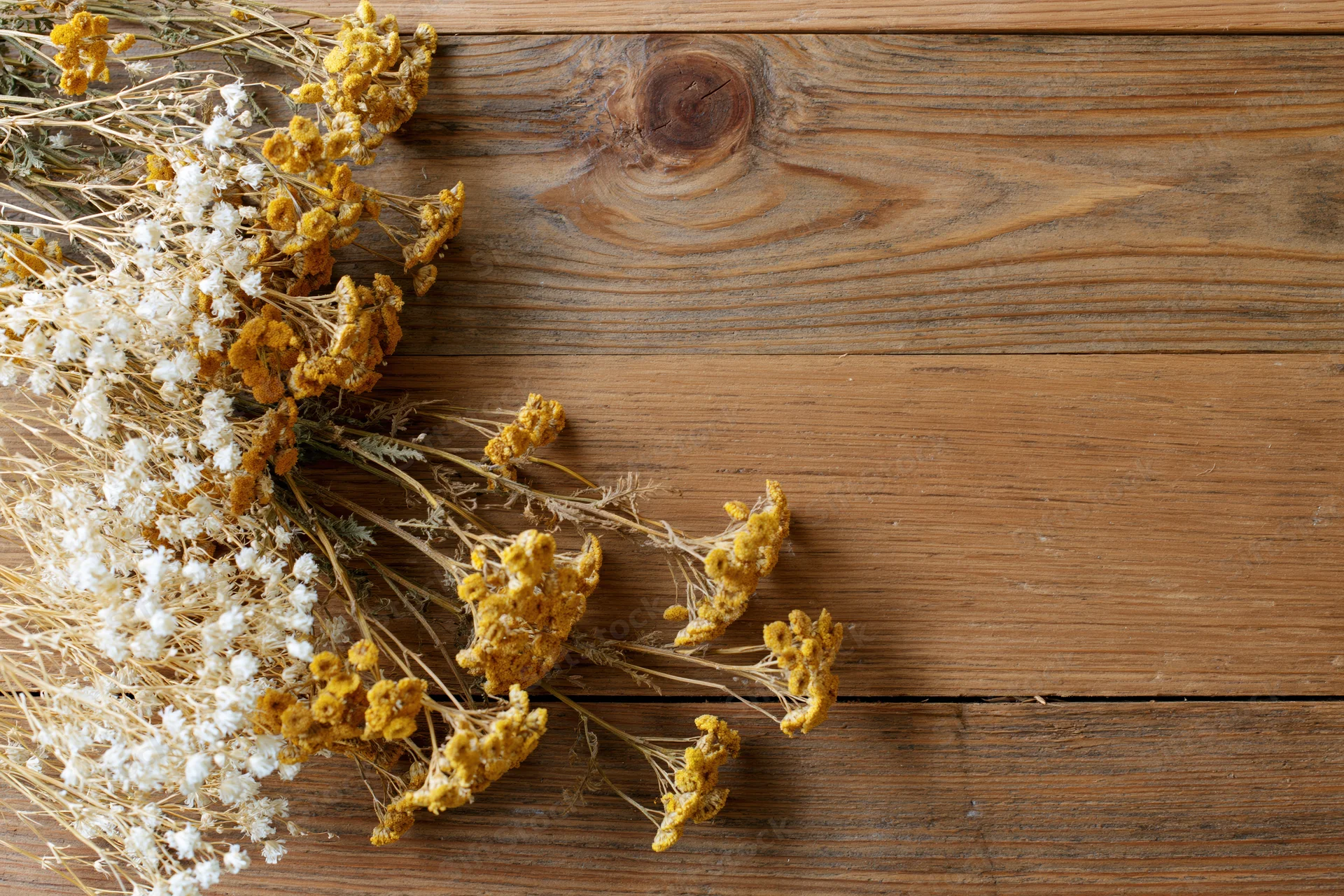 Dried wildflowers and tansy blooms arranged on a wooden table with copyspace
