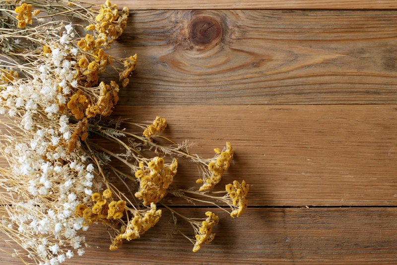 Dried wildflowers and tansy blooms arranged on a wooden table with copyspace