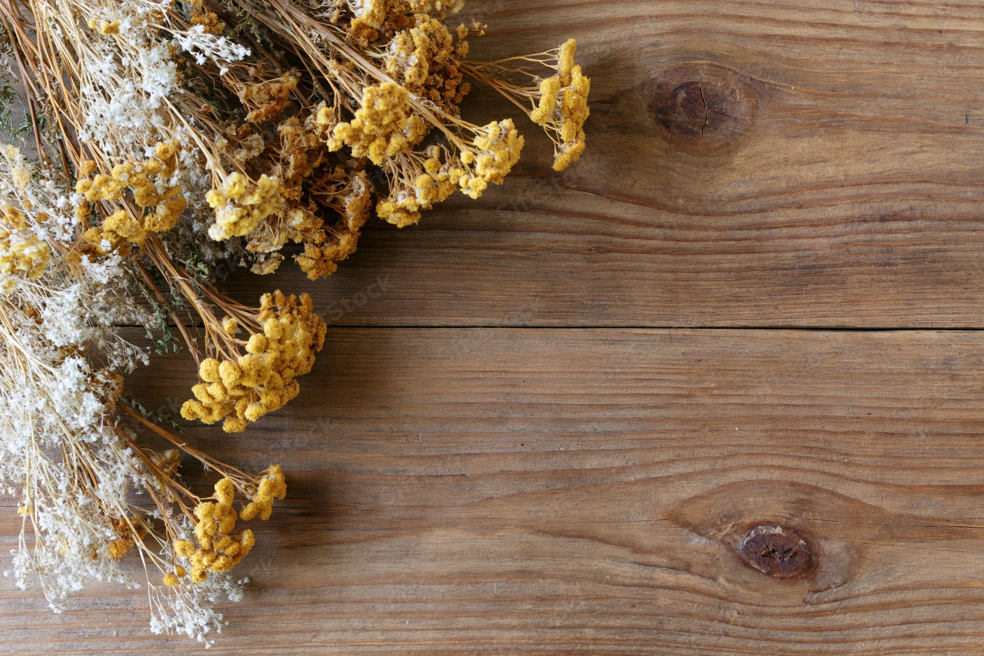 Dried wildflowers and tansy blooms arranged on a wooden table with copyspace