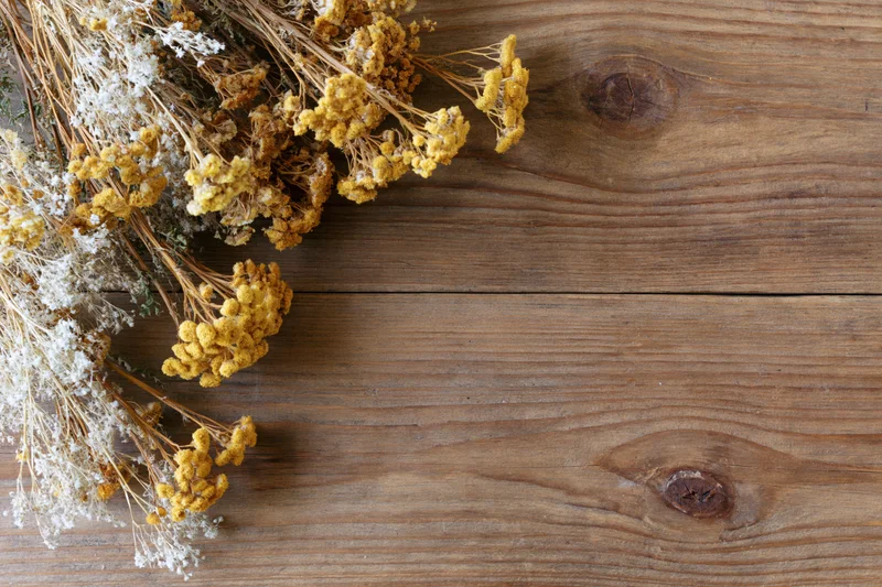 Dried wildflowers and tansy blooms arranged on a wooden table with copyspace