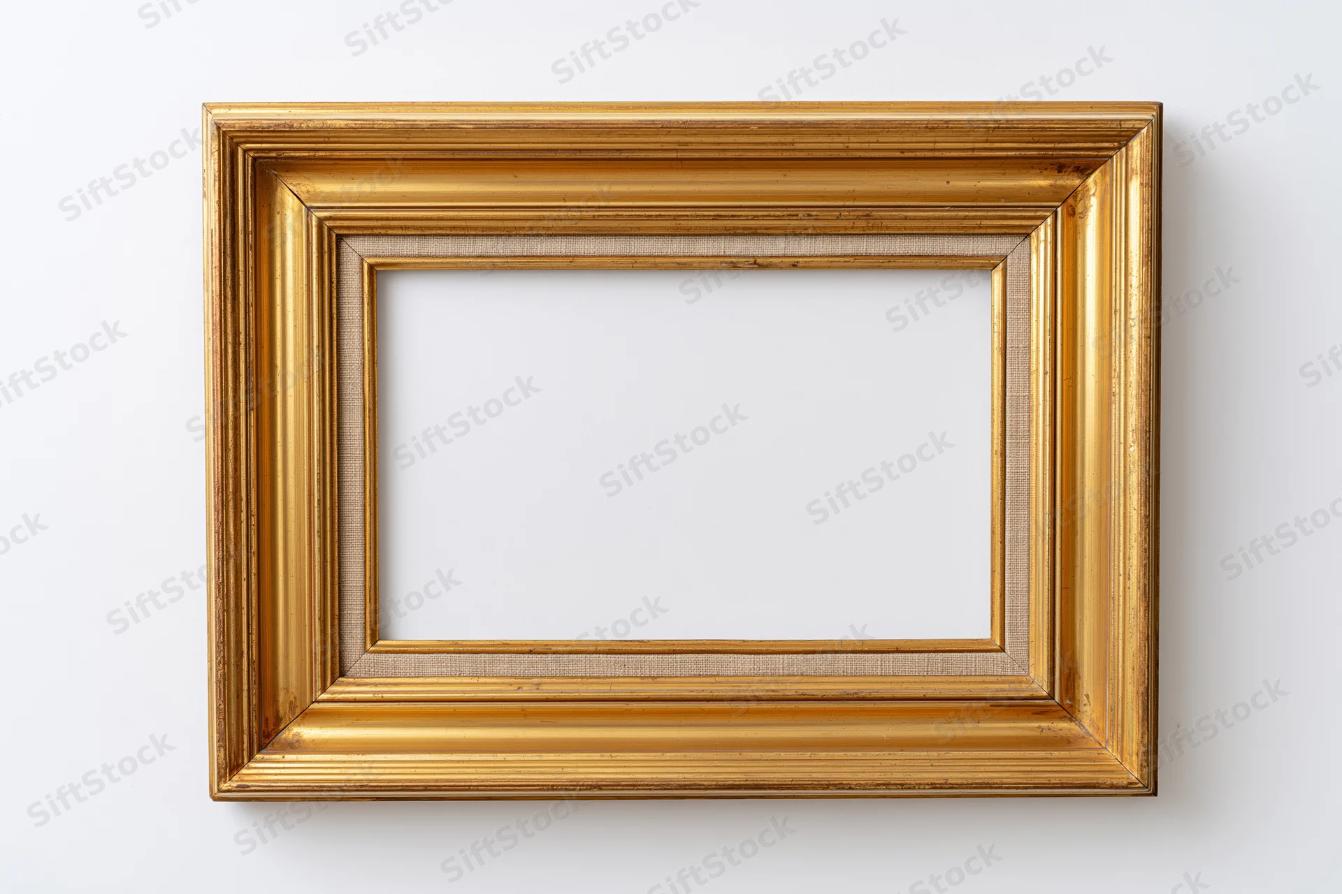Empty antique gold picture frame hanging on a white wall